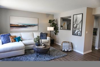 Sorelle Apartments model living room with white couch, blue accent pillows, a shag rug and abstract art